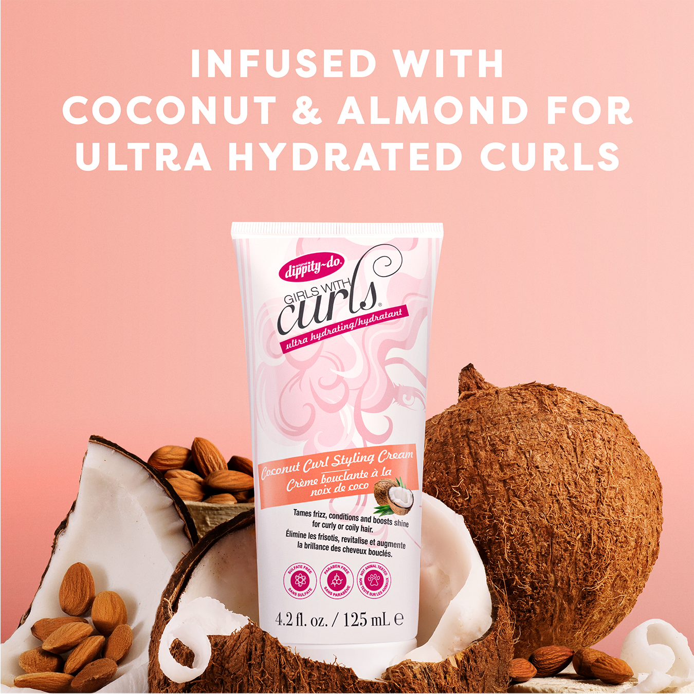 Tube of hair styling cream with coconut and almond ingredients on a pink background
